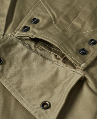 Khaki green jacket sleeve cuff with snap buttons and stitched pocket flap detail