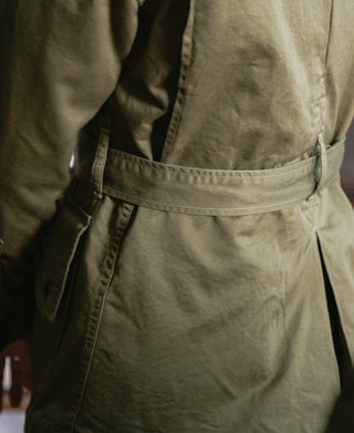 Khaki green M-42 jacket close-up showing pleated waist and buttoned pocket flaps
