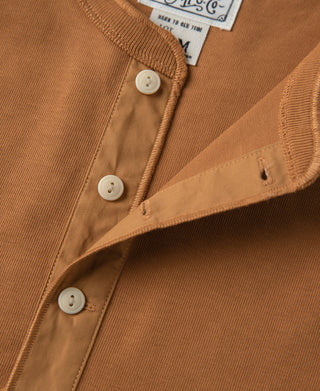 Vintage long-sleeve henley shirt detail: dark orange button placket and small chest emblem