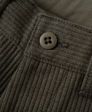 Close-up of dark coffee cotton trousers with round button and pique stripe weave.