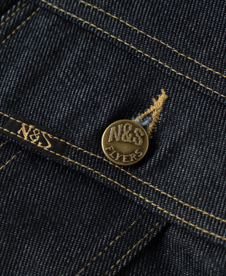 Gold-tone “N&S Flyers” coin logo button on indigo denim with yellow topstitching