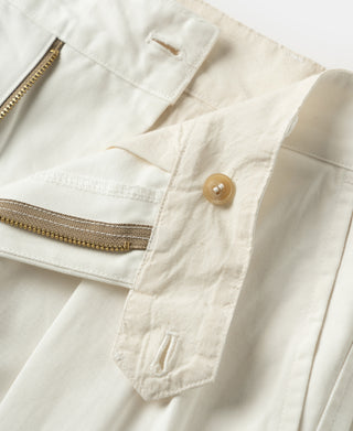 White trousers showing side pocket flap, button, and waistband stitching.