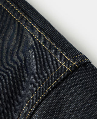 Close-up of indigo denim cuff seam with double yellow stitching and folded edge