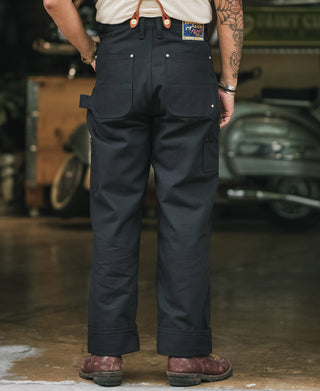 Navy work pants with knee panels, cargo-style pockets, and leather front strap tabs