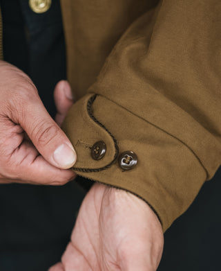 Brown jacket cuff with snap button and stitched placket; houndstooth lining